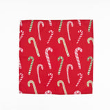 Red cloth dinner napkins featuring playful pink, white, and green candy cane patterns for Christmas tablescapes.