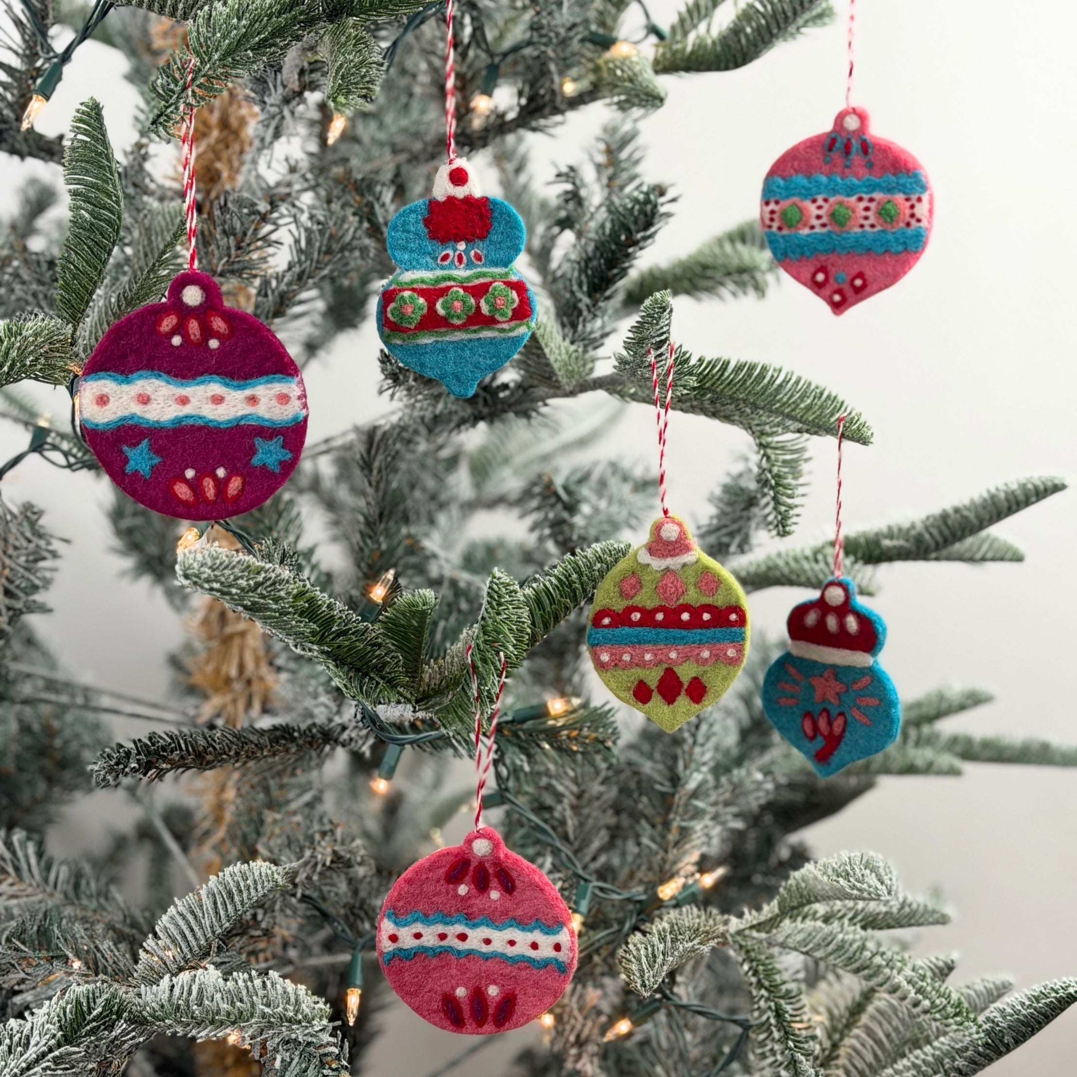 Six Colorful felt Christmas ornaments featuring festive bauble shapes, intricate embroidered patterns, and cheerful holiday colors.