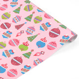 A roll of pink holiday wrapping paper featuring a colorful Christmas ornament pattern, shown on a clean white background.