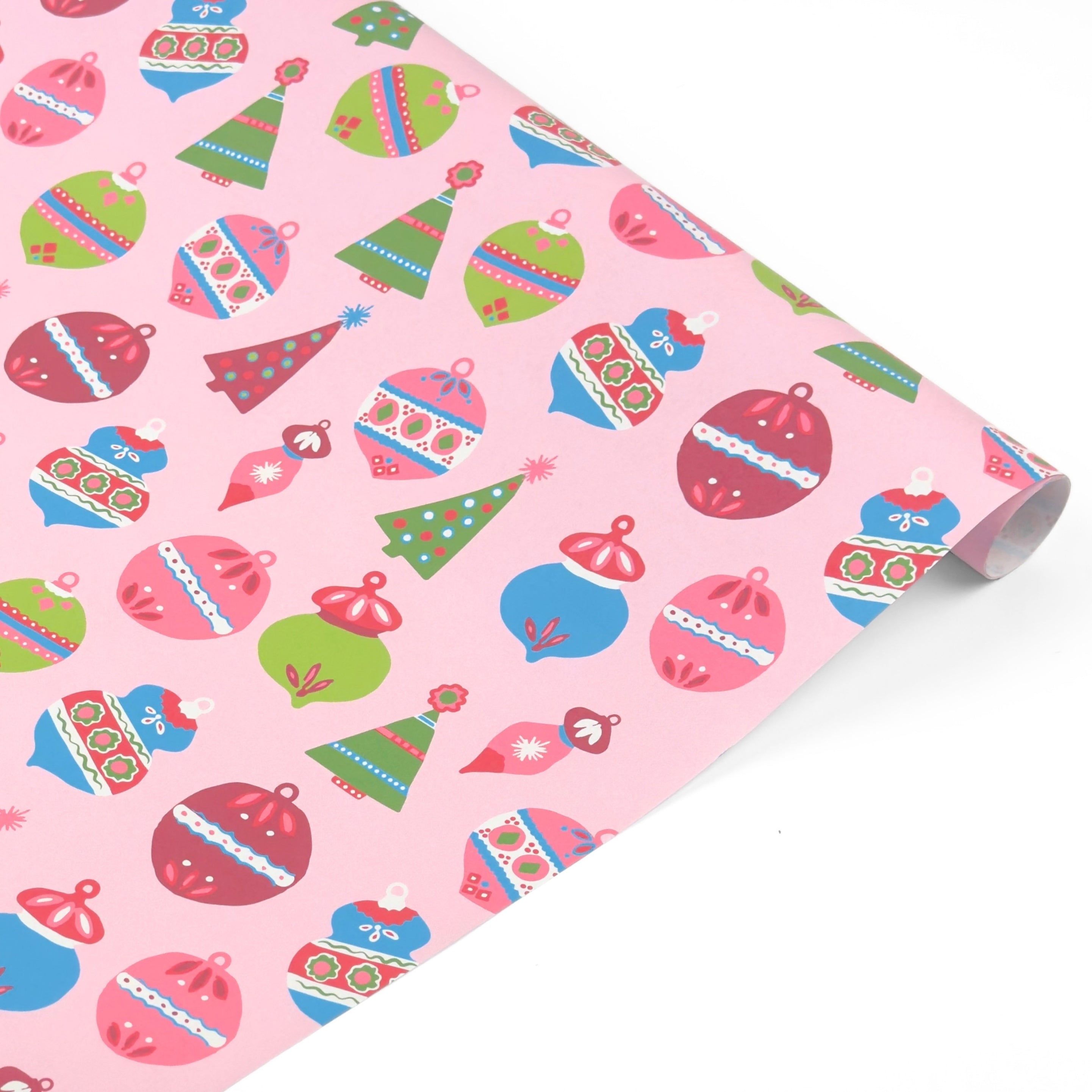 A roll of pink holiday wrapping paper featuring a colorful Christmas ornament pattern, shown on a clean white background.