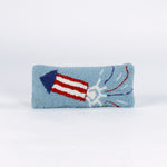 Rectangular blue decorative pillow with a hooked texture featuring a red, white, and blue fireworks rocket design, shown on a white background.