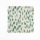 White cloth dinner napkins featuring abstract green brushstroke patterns in varying shades for stylish tablescapes.