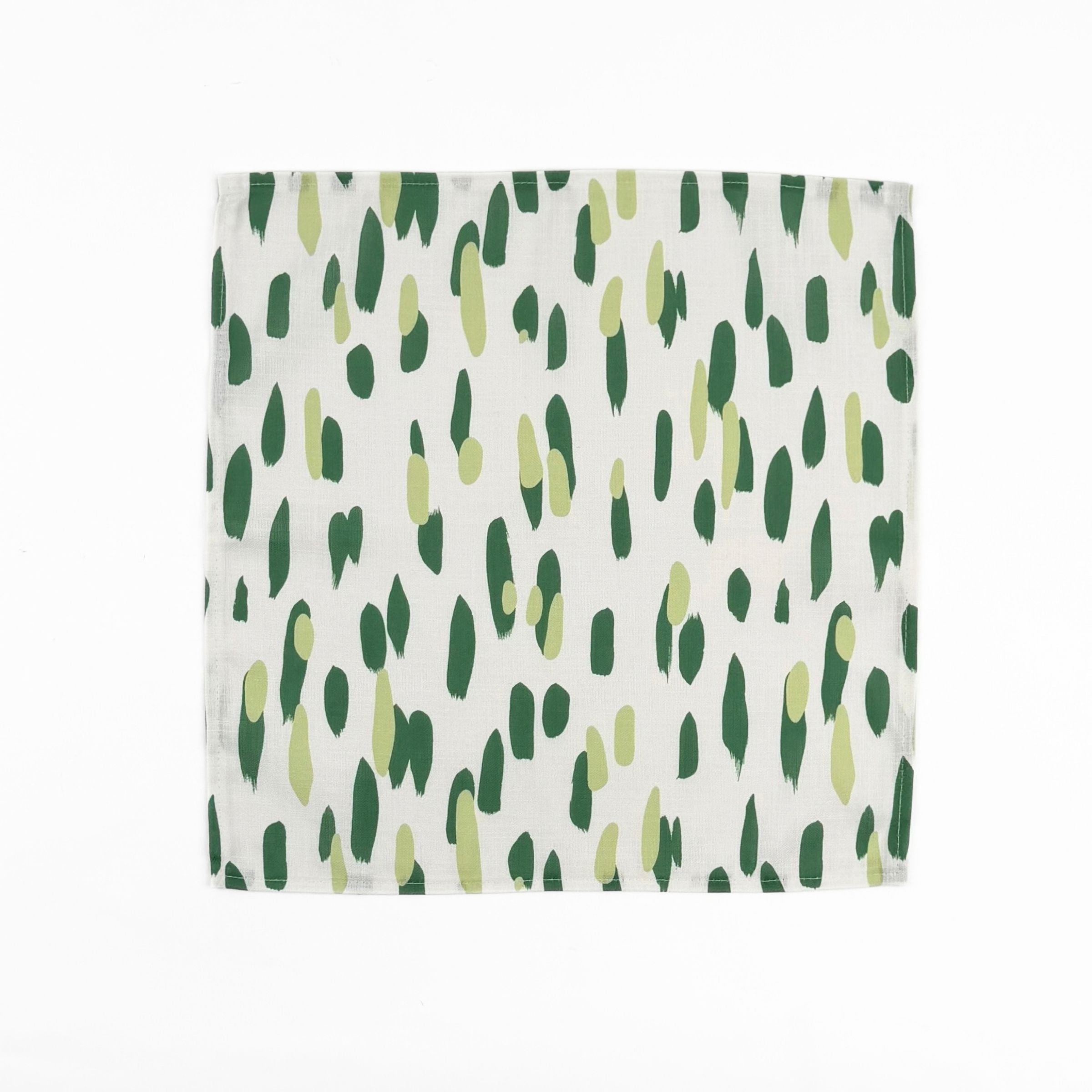 White cloth dinner napkins featuring abstract green brushstroke patterns in varying shades for stylish tablescapes.