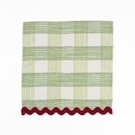 Green and white gingham cloth dinner napkins featuring red scalloped trim for charming holiday tablescapes.
