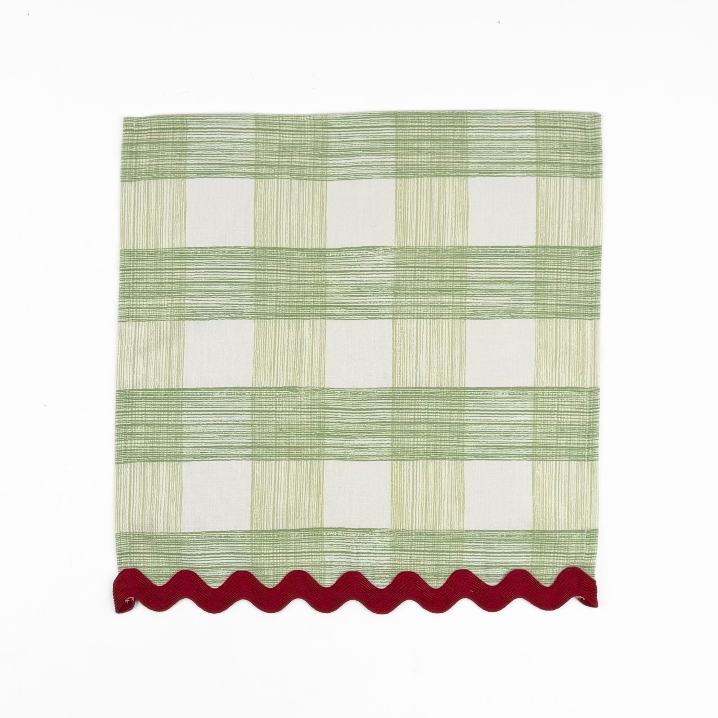 Green and white gingham cloth dinner napkins featuring red scalloped trim for charming holiday tablescapes.
