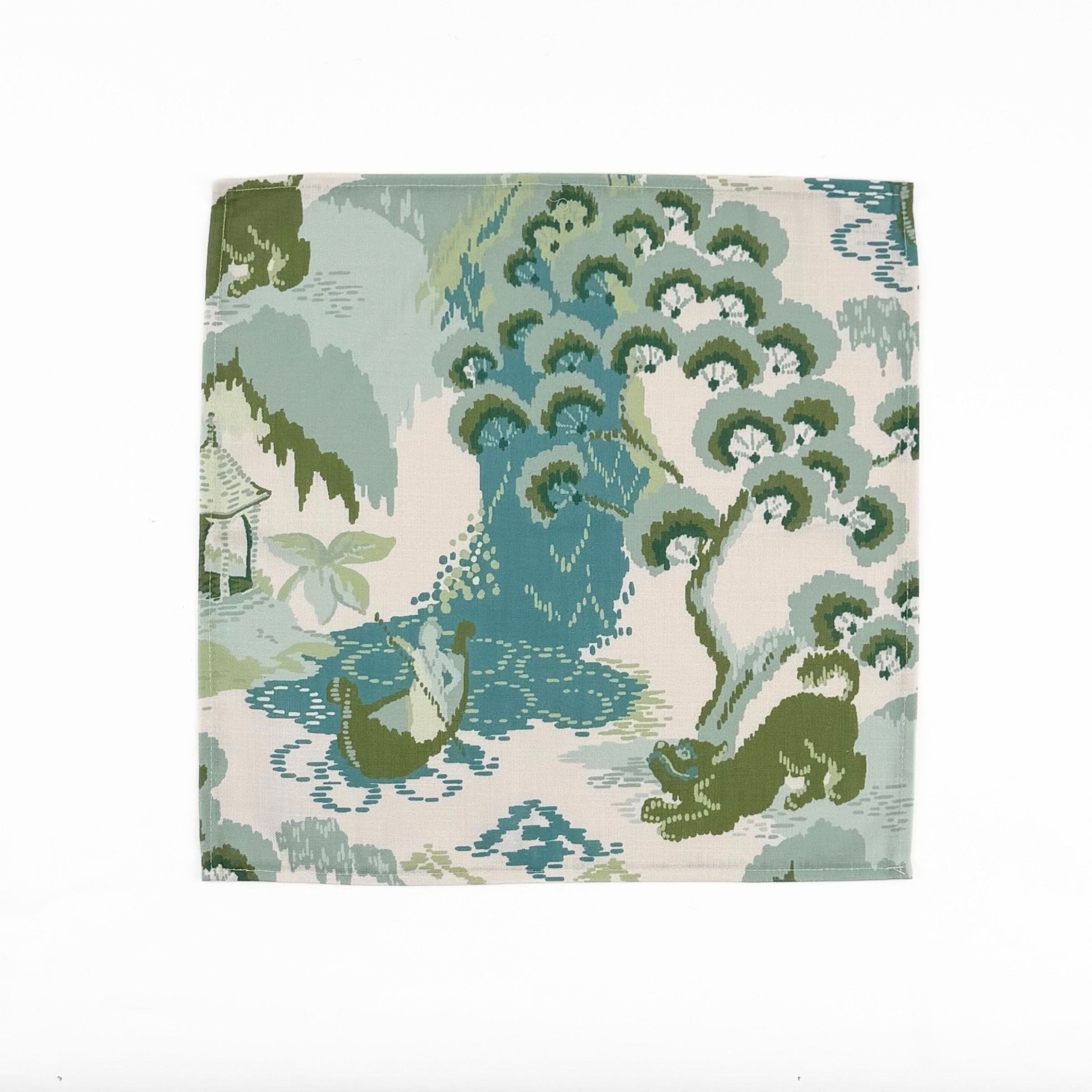 Elegant cloth dinner napkins featuring traditional chinoiserie landscapes in soft green, blue, and ivory tones.