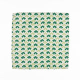 White cloth dinner napkins featuring geometric green triangle patterns in two shades for stylish tablescapes.