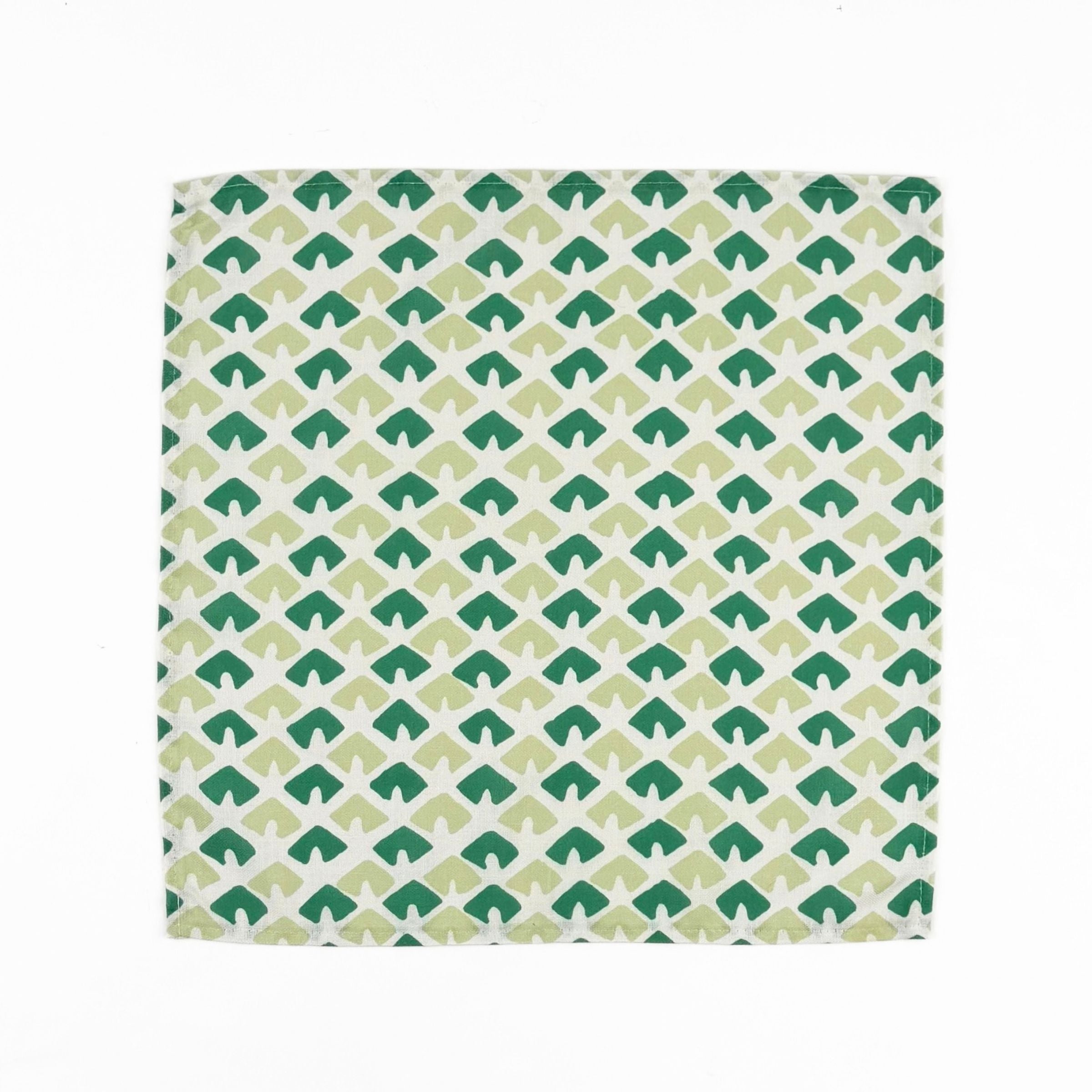 White cloth dinner napkins featuring geometric green triangle patterns in two shades for stylish tablescapes.