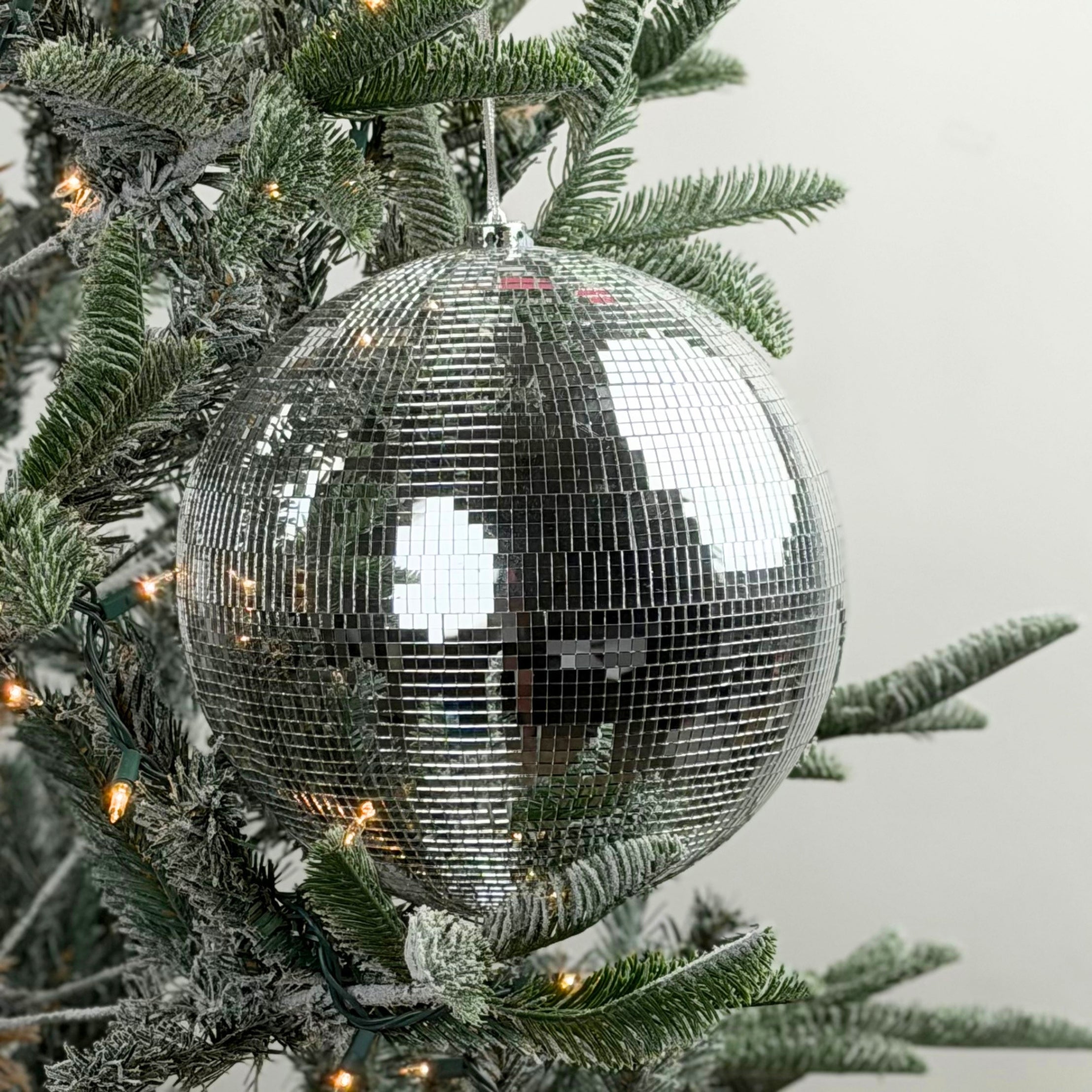 Large mirrored disco ball Christmas ornament featuring shimmering silver tiles, perfect for festive holiday decorating.