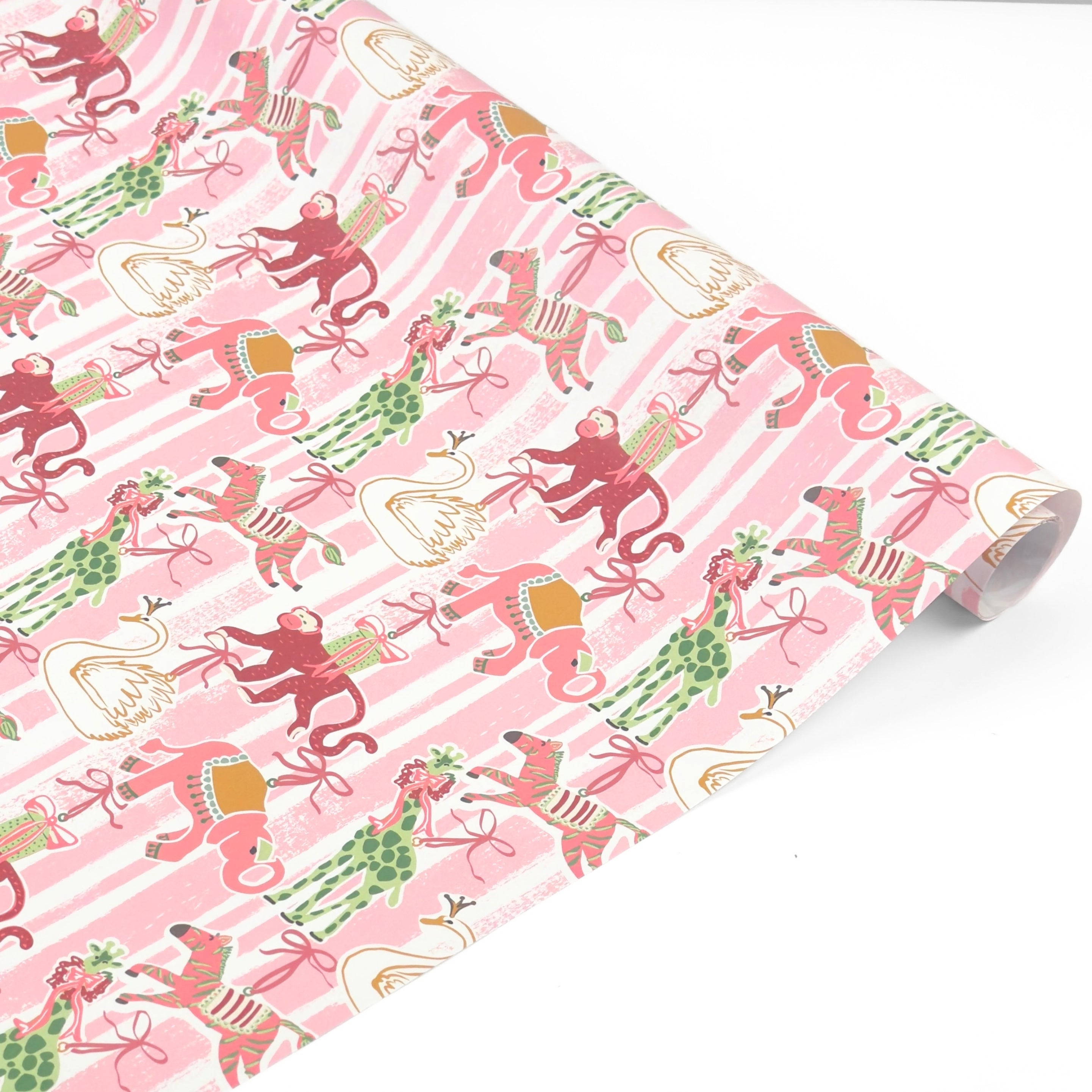 Whimsical Christmas gift wrap featuring festive giraffes, monkeys, zebras, and swans against playful pink stripes.