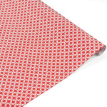 A roll of red gift wrap with a white chinoiserie lattice pattern. 