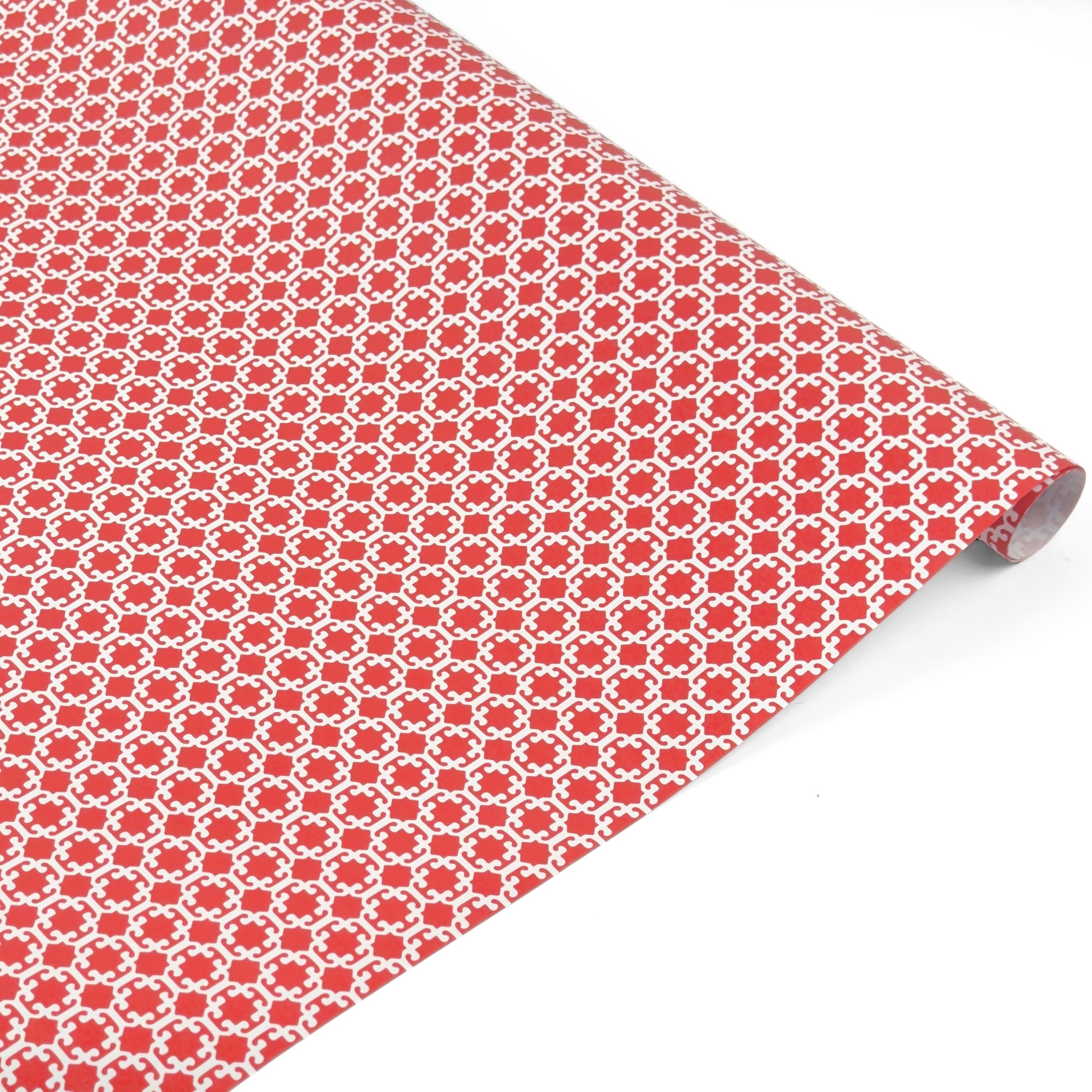 A roll of red gift wrap with a white chinoiserie lattice pattern. 