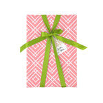 a wrapping paper with a geometric lattice pattern in pink with green ribbon and a gift tag