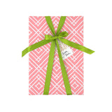 a wrapping paper with a geometric lattice pattern in pink with green ribbon and a gift tag