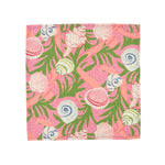 Pink cloth dinner napkins featuring colorful seashells, tropical green foliage, and playful coastal inspired patterns.