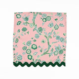 Pink cloth dinner napkins featuring elegant green chinoiserie florals, delicate branches, and dark green trim.