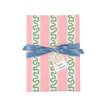 Front view of a present wrapped in pink and green Christmas wrapping paper with red ribbon and a paper tag