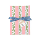 Front view of a present wrapped in pink and green Christmas wrapping paper with red ribbon and a paper tag