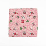 Pink Christmas dinner napkins featuring swirling ribbons, nutcrackers, ballerinas, festive gifts, and whimsical holiday illustrations.