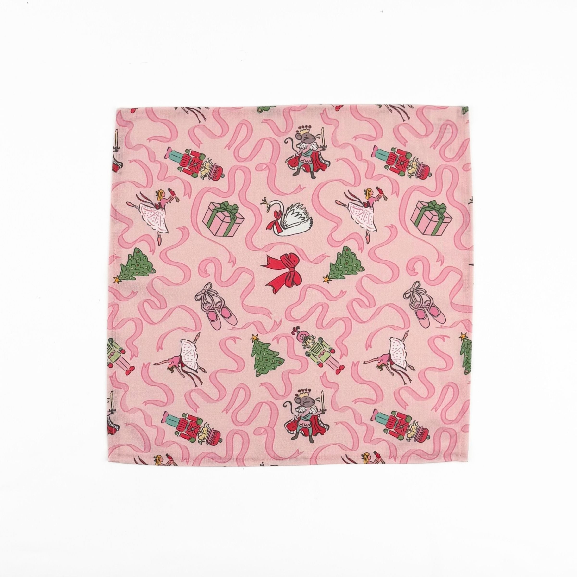 Pink Christmas dinner napkins featuring swirling ribbons, nutcrackers, ballerinas, festive gifts, and whimsical holiday illustrations.