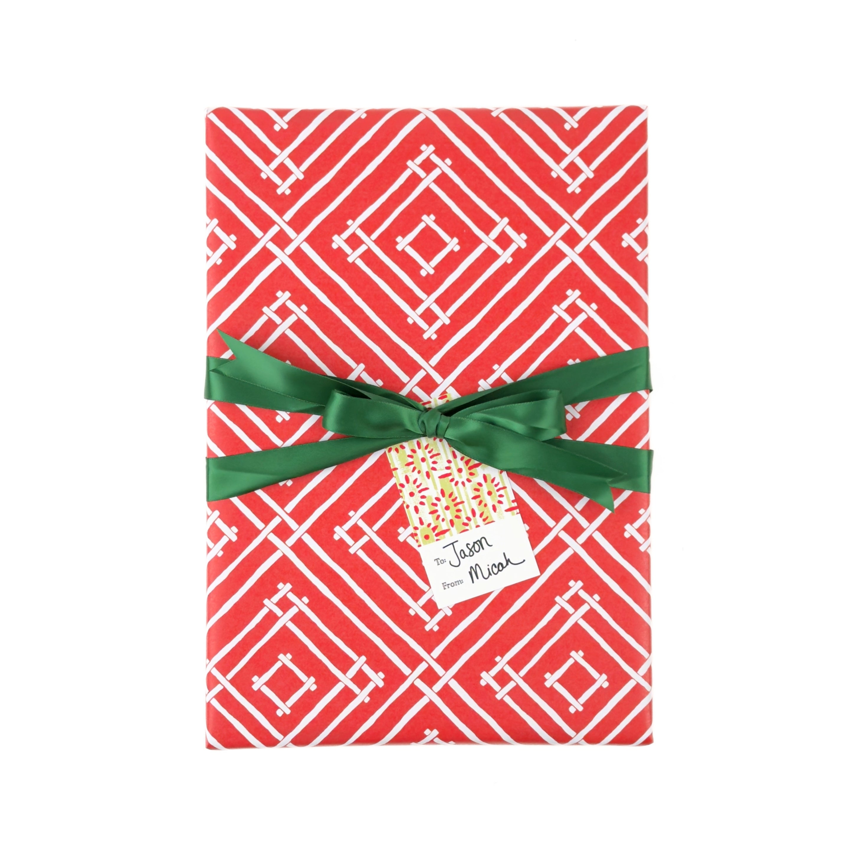 Red wrapping paper with a white geometric diamond pattern, wrapped around a gift box tied with a green ribbon and a small decorative tag