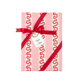 red and pink striped wrapping paper in fancy stripe patterns wrapped in a red ribbon and a gift tag