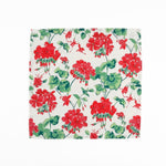 White cloth dinner napkins featuring vibrant red geranium flowers and lush green leaves for tablescapes.