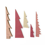 5 paper christmas trees in their folded down format in shades of pink, red, beige, and mauve, arranged upright on a plain white background.