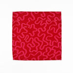 Red cloth dinner napkins featuring playful pink swirling ribbon patterns, perfect for festive table settings.