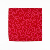 Red cloth dinner napkins featuring playful pink swirling ribbon patterns, perfect for festive table settings.