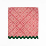 Pink cloth dinner napkins featuring red bamboo trellis patterns and dark green scalloped trim accents.