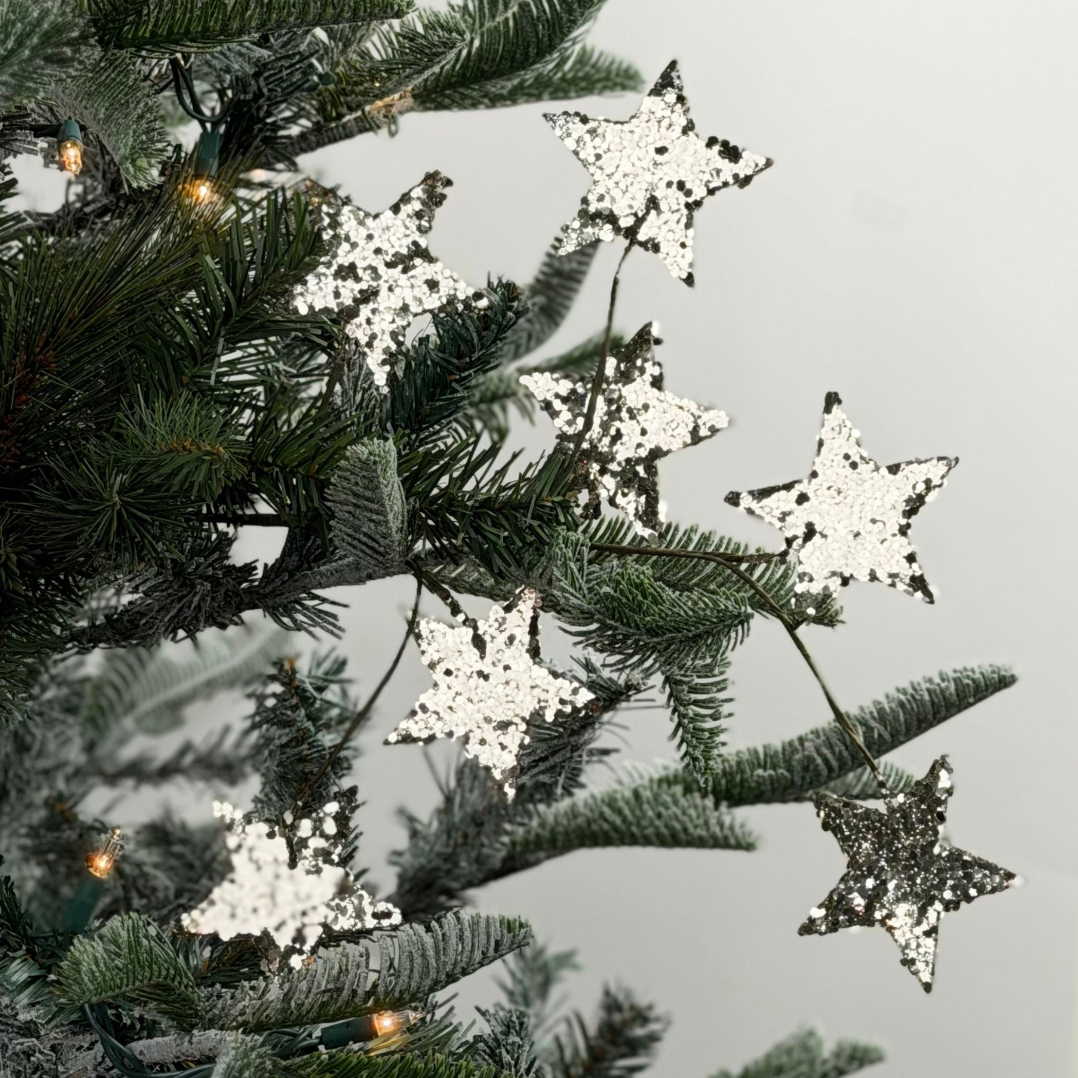 Silver spray of stars featuring sparkling glitter accents, perfect for festive Christmas trees and arrangements.