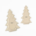 Reverse side of two ceramic Christmas tree-shaped plates shown on a plain white background, displaying their printed back sides with product information labels.