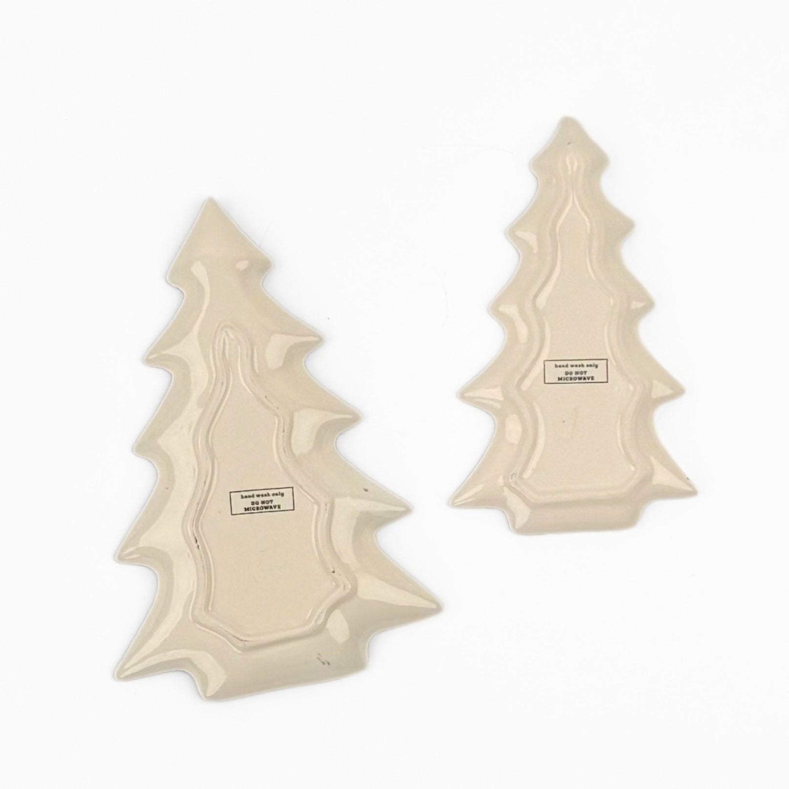 Reverse side of two ceramic Christmas tree-shaped plates shown on a plain white background, displaying their printed back sides with product information labels.