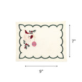 Elegant white cocktail napkins featuring green scalloped borders, embroidered Santa faces, holly, and pink ornaments with dimensions of 7" by 9"