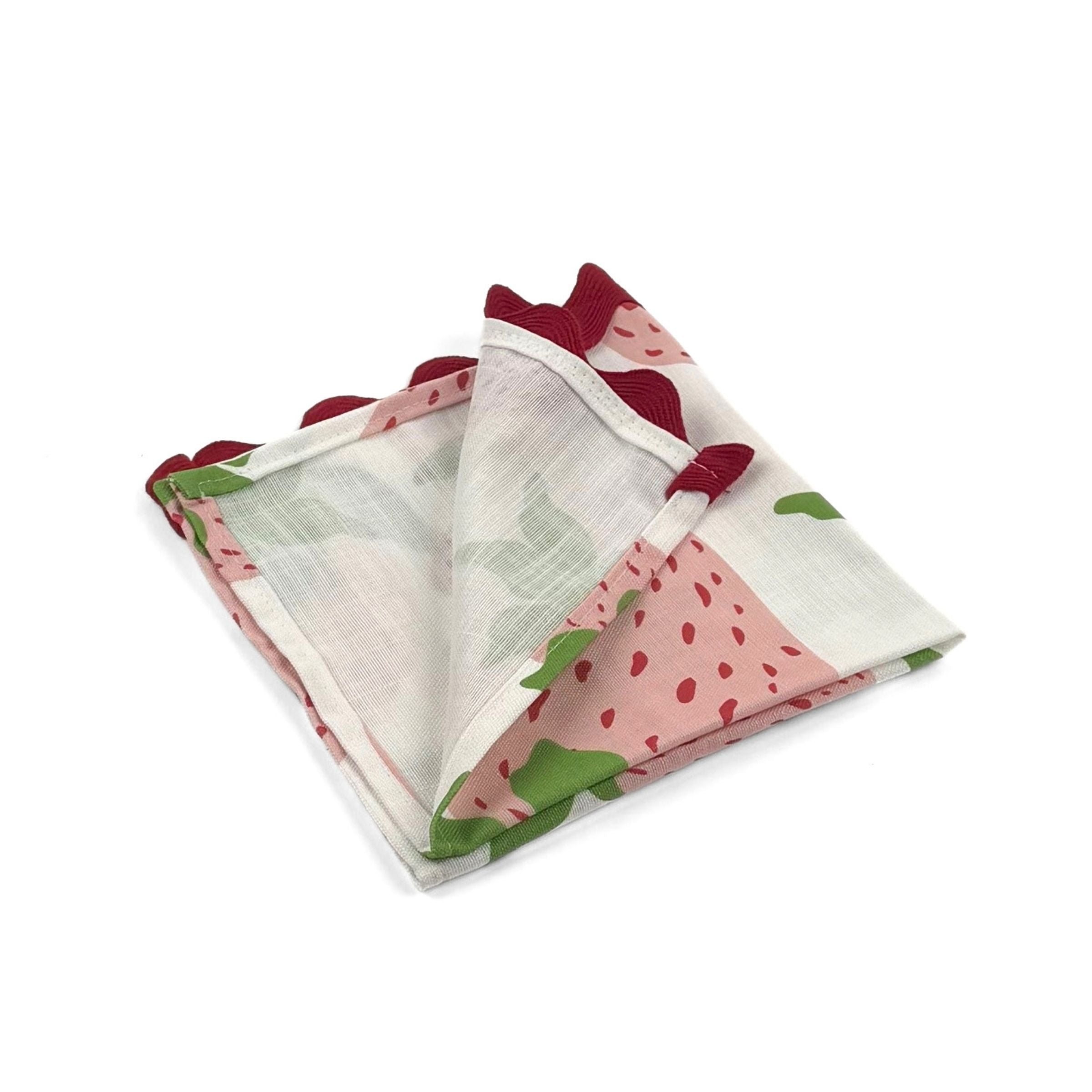 Folded White cloth dinner napkins featuring pink strawberries, green leaves, and red scalloped trim for tablescapes.
