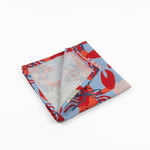 Folded Blue cloth dinner napkins featuring vibrant red lobsters, seashells, and playful coastal patterns for entertaining.