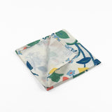 Folded White cloth dinner napkins featuring vibrant strawberries, yellow lemons, blue flowers, and lush green foliage.