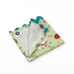 Folded Light green Christmas dinner napkins featuring festive pugs, holiday decorations, and bright turquoise ric rac trim.