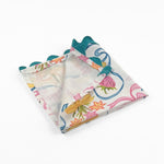 Folded White dinner napkins featuring playful bunnies, colorful bows, strawberries, flowers, and turquoise ric rac trim.