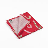 Folded Red cloth dinner napkins featuring playful pink, white, and green candy cane patterns for Christmas tablescapes.
