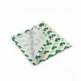 Folded White cloth dinner napkins featuring geometric green triangle patterns in two shades for stylish tablescapes.