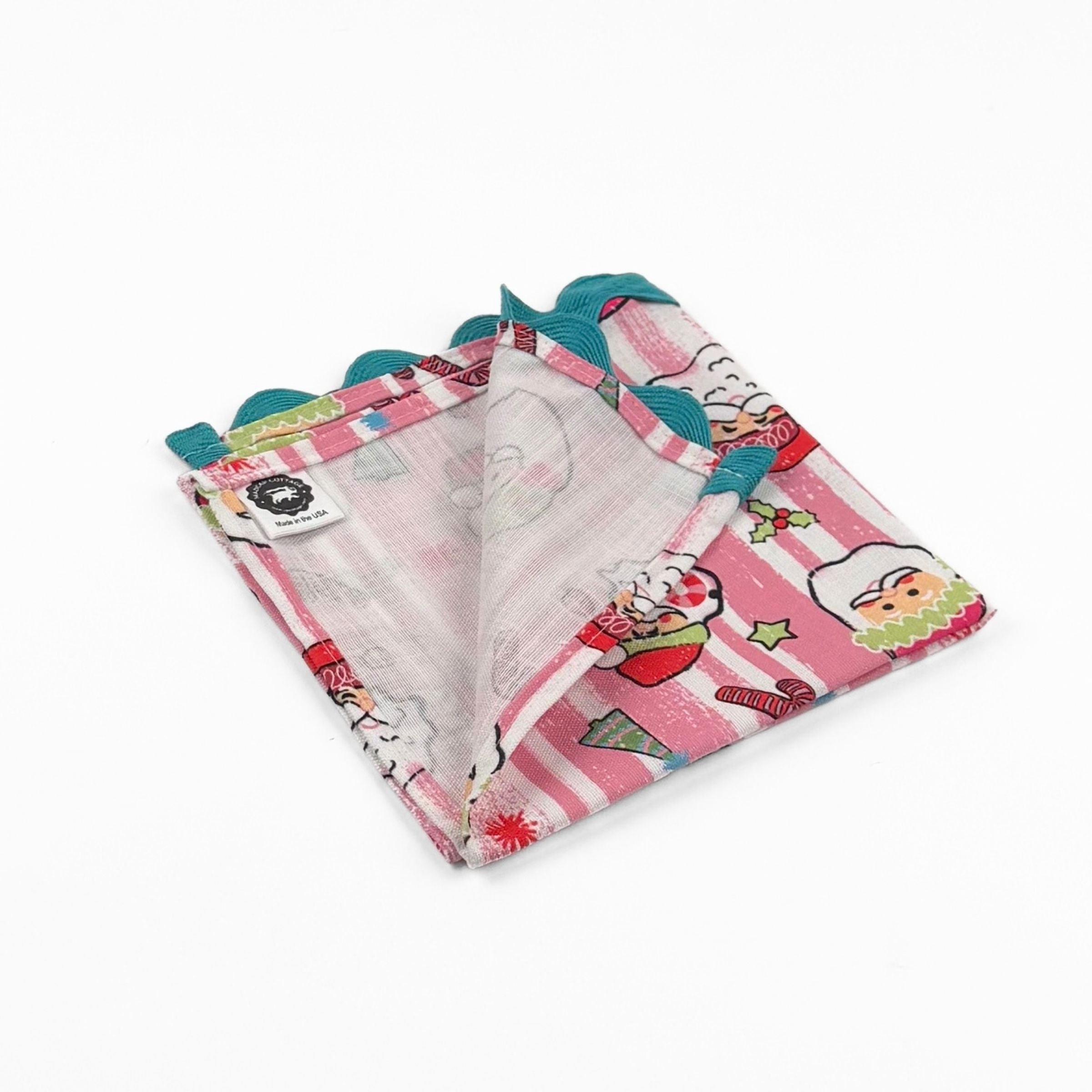 Folded Pink striped Christmas dinner napkins featuring cheerful Santa faces, festive motifs, and turquoise ric rac trim.