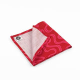 Folded Red cloth dinner napkins featuring playful pink swirling ribbon patterns, perfect for festive table settings.