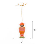 Pink hand painted wooden nutcracker Christmas ornament on a white background with dimension arrows indicating 5" by 2"
