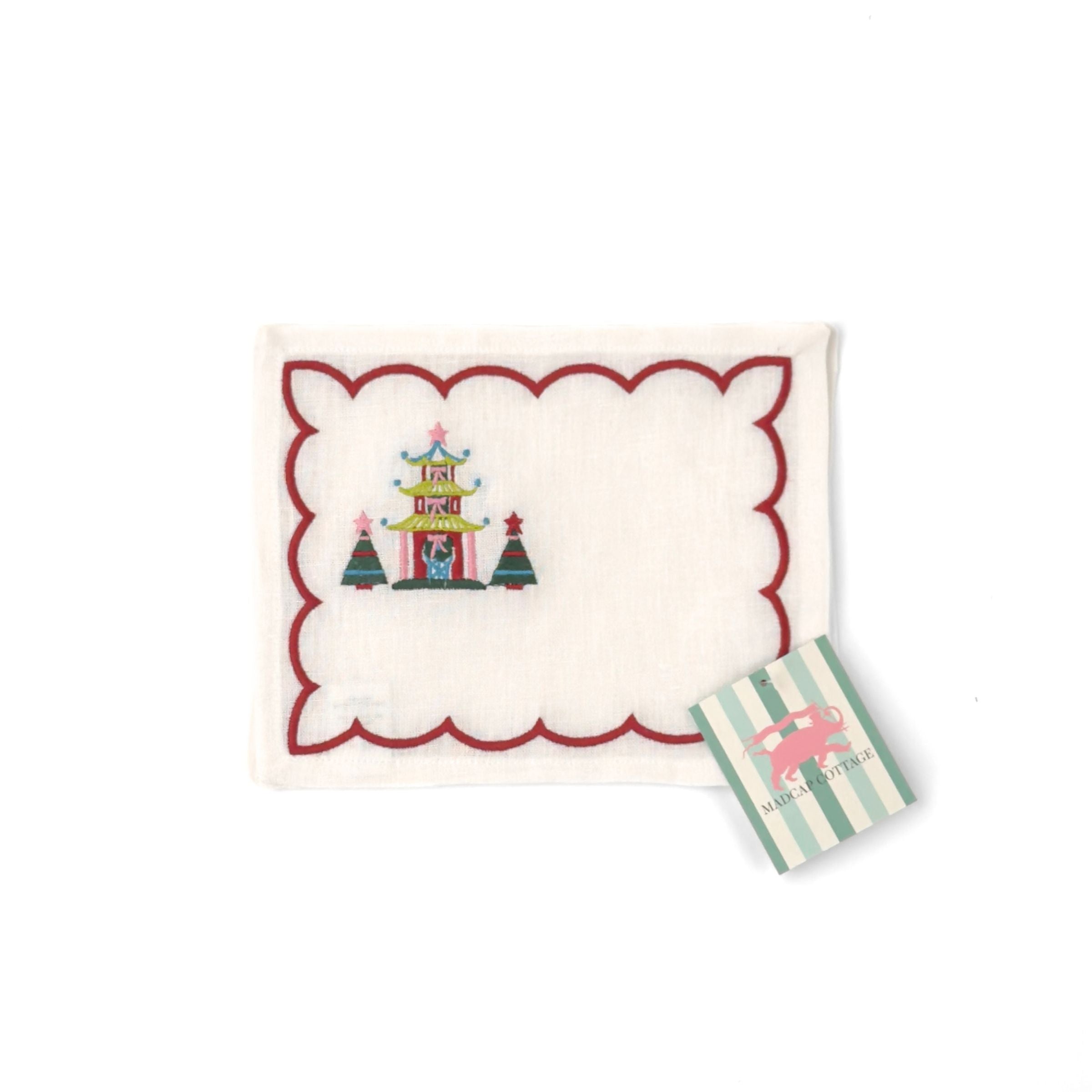 Elegant white cocktail napkins featuring red scalloped borders, colorful Christmas pagodas, festive trees, and embroidery.