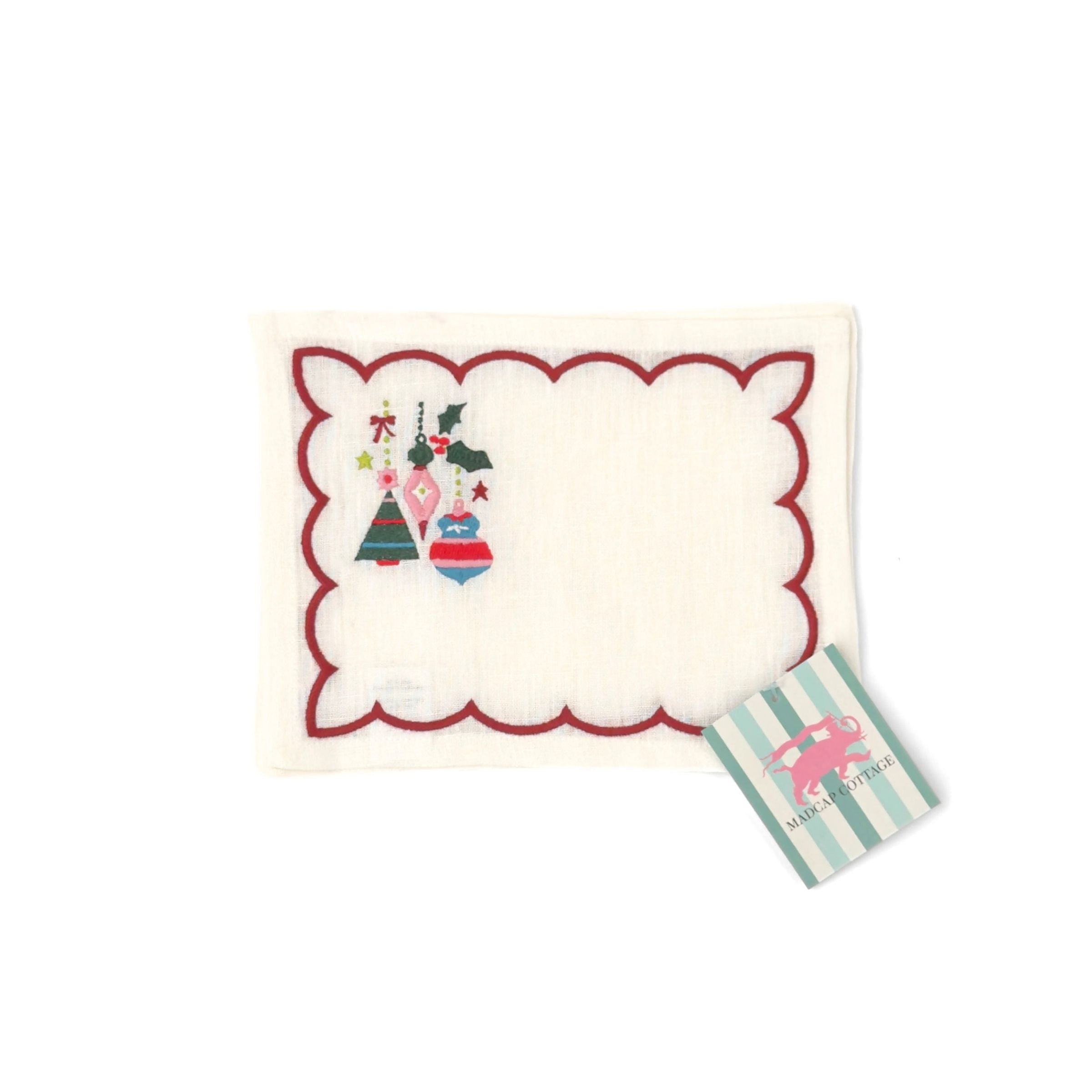 Elegant white cocktail napkins featuring red scalloped borders, colorful Christmas ornaments, holly, and festive embroidery.