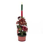 A large metal handpainted Christmas candle holder featuring red poinsettia flowers and green holly leaves with a pink base. 