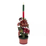 A large metal handpainted Christmas candle holder featuring red poinsettia flowers and green holly leaves with a pink base. 