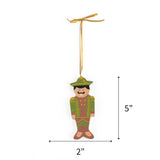Green hand painted wooden nutcracker Christmas ornament on a white background with dimension arrows indicating 5" by 2"